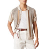 Person wearing a striped shirt over a white t-shirt with white pants on a light background