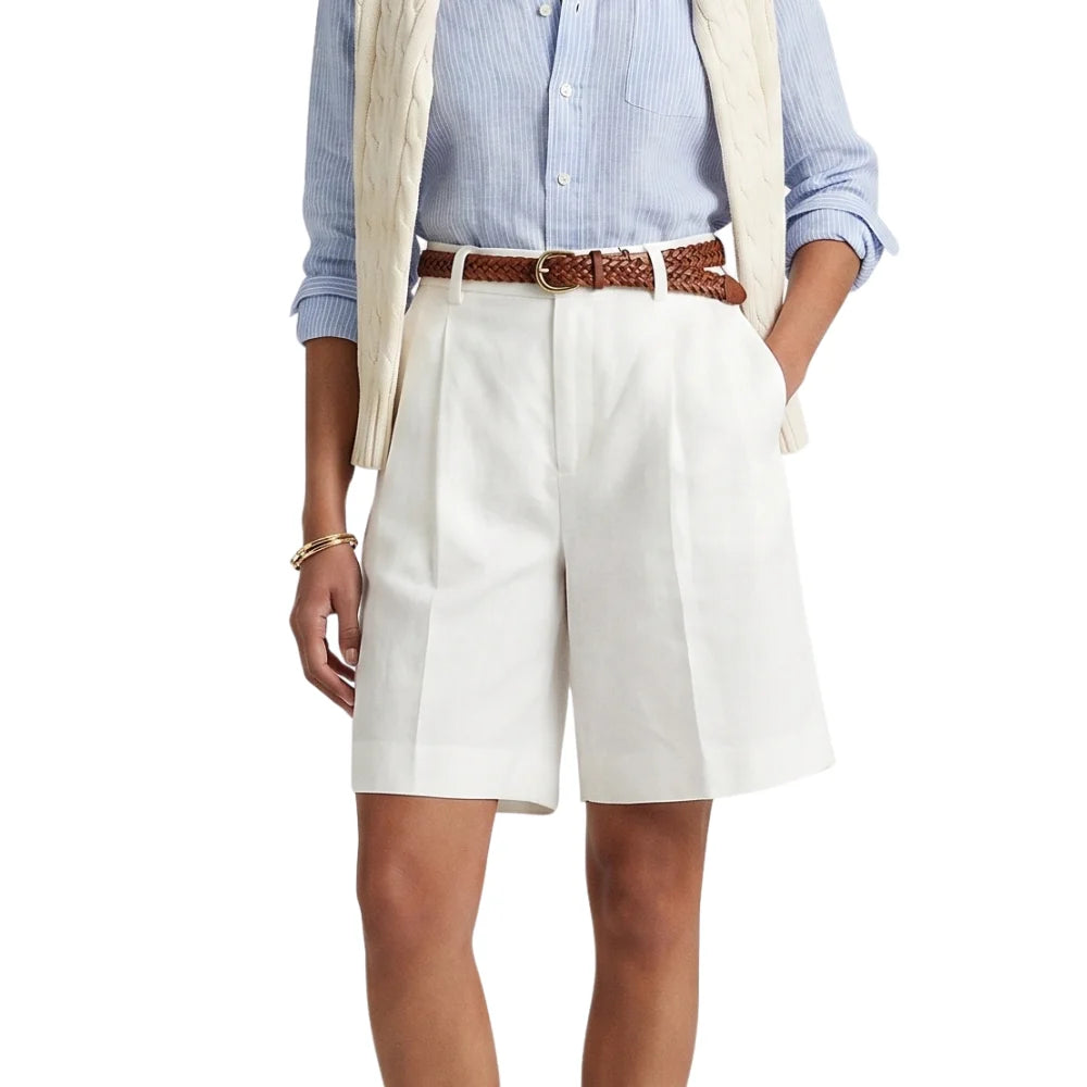 Person wearing a light blue button-up shirt, beige vest, white shorts, and a brown belt on a white background.
